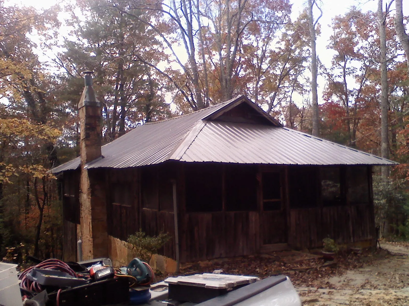 Brown metal hip roof on an old cabin with a stone chimney in Oxford